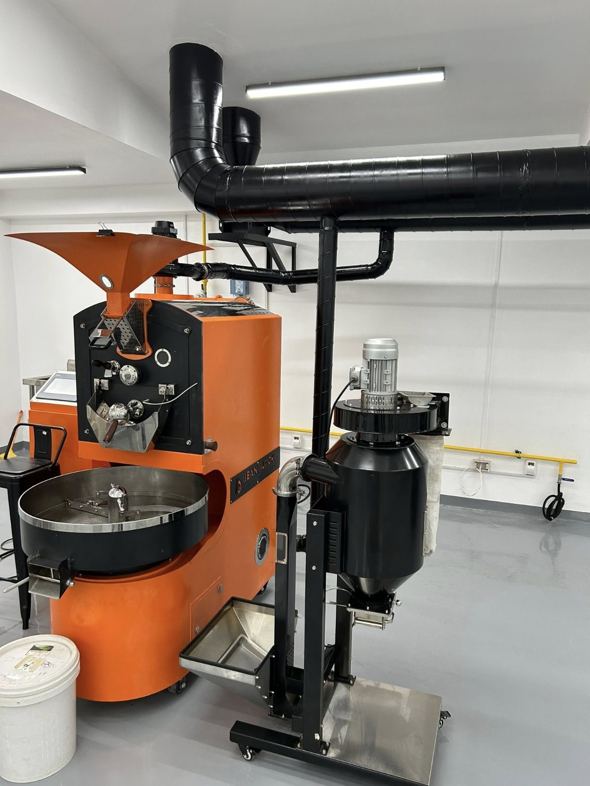 Close-up of the commercial drum roaster and afterburner unit - purpose-built roastery room with controlled airflow and enclosed design